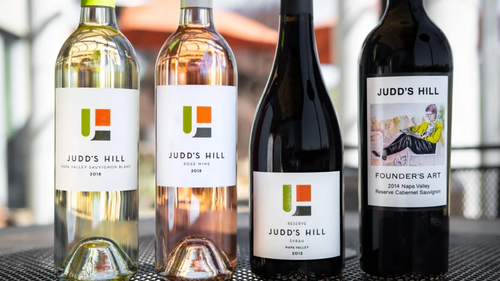 Four Judd's Hill wine bottles displayed including Sauvignon Blanc, Rosé, Syrah Reserve, and Founder's Art Cabernet Sauvignon showcasing the winery's diverse wine collection