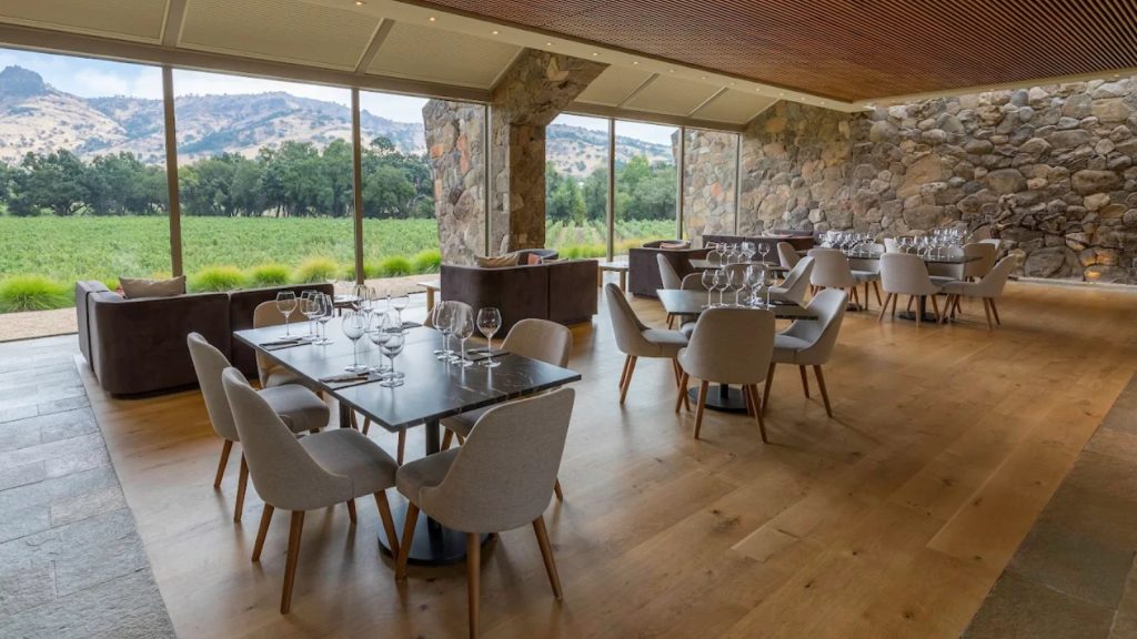 Stag's Leap Wine Cellars modern tasting room with stone columns, floor-to-ceiling windows overlooking vineyards, elegant dining tables, and mountain views