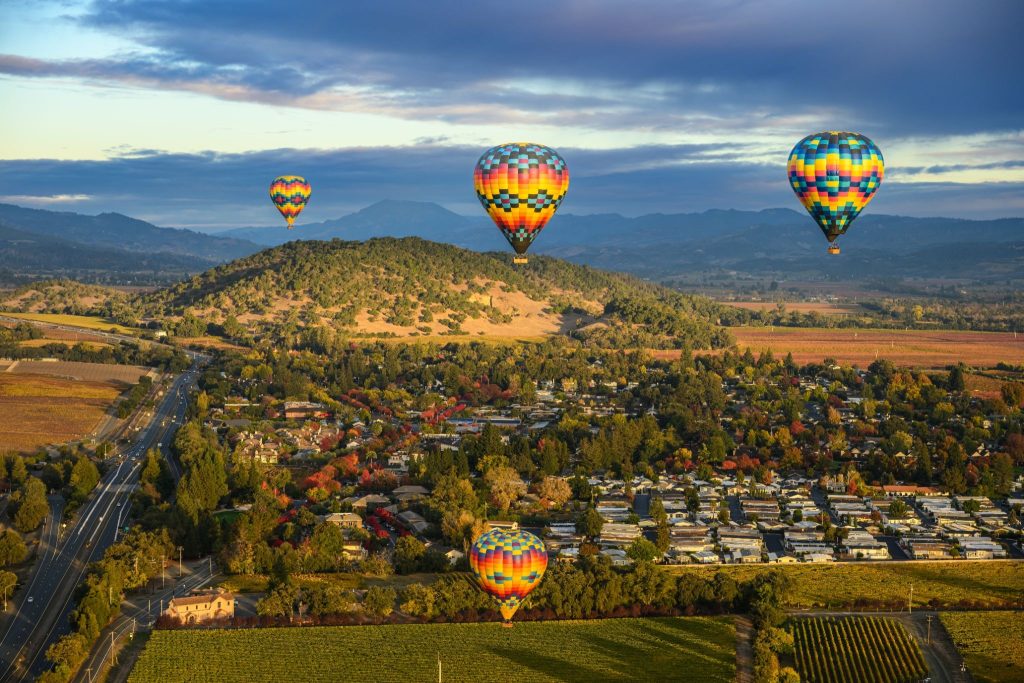 Hot air balloons flying over Napa Valley vineyards near Sonoma Valley luxury hotels at sunrise