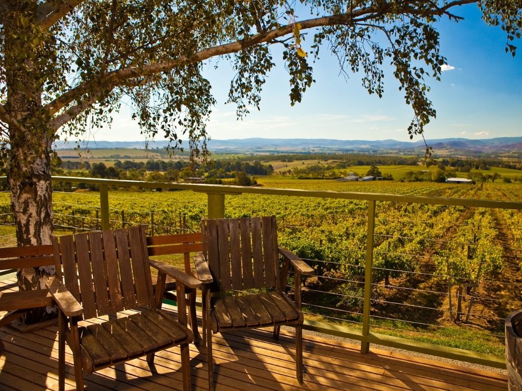 Wooden patio chairs overlooking Napa Valley vineyards and rolling hills