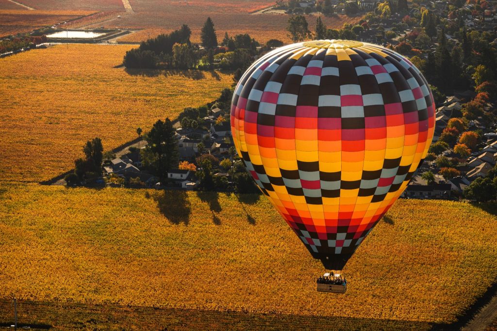 Napa Valley Aloft hot air balloon floating above Napa Valley vineyards during golden hour