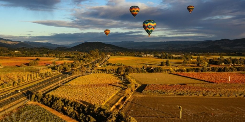 Aloft Hot air balloons flying over Napa Valley vineyards during sunrise near Yountville.