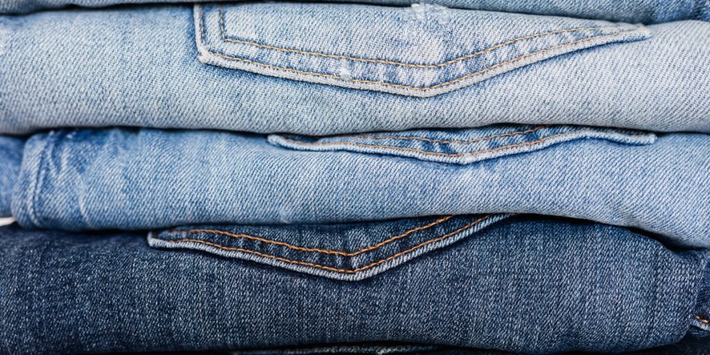 What to Wear on a Hot Air Balloon Ride in Napa Valley - a close-up of three folded pairs of light blue and dark denim jeans with visible stitching and seams, showing comfortable casual clothing options for the adventure