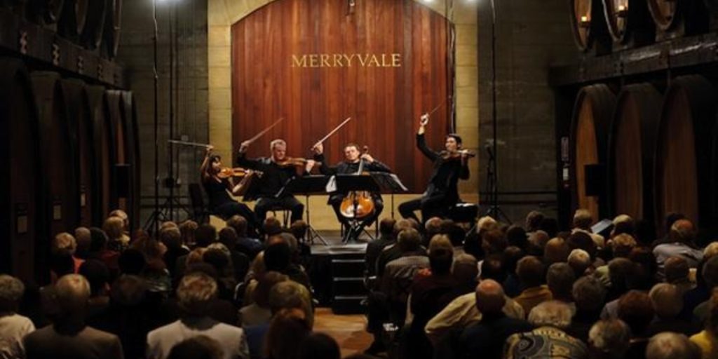 Music in the Vineyards event at Merryvale featuring a classical string quartet performing on stage for an engaged audience in an elegant winery venue with warm lighting.